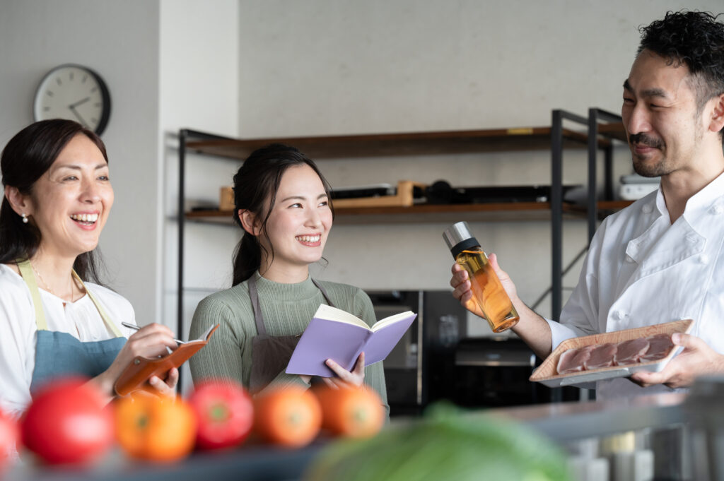 イメージ写真：料理人から説明を受けるメモを手にした女性二人